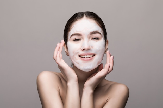 Beautiful woman with facial mask on white wall. Cosmetics, skin care.