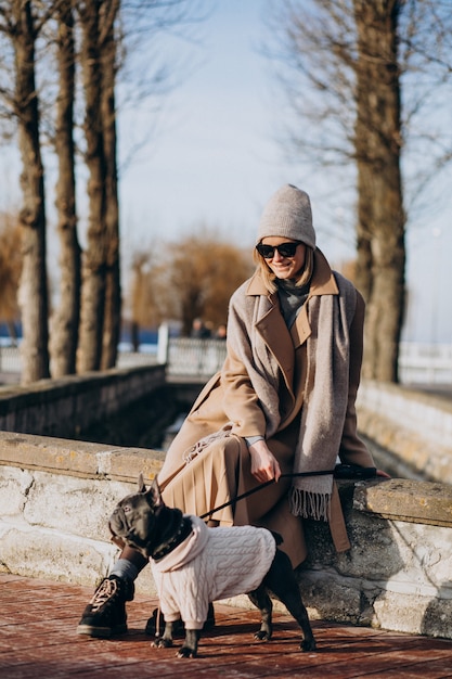 Free Photo beautiful woman with french bulldog walking in park