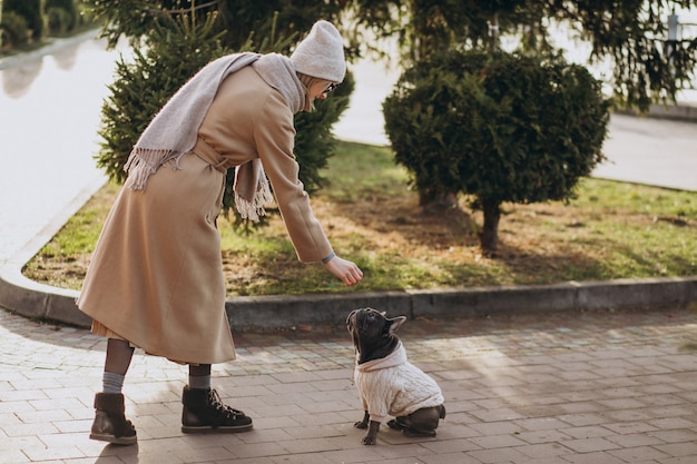 Free Photo beautiful woman with french bulldog walking in park