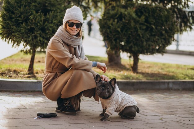 Beautiful woman with french bulldog walking in park