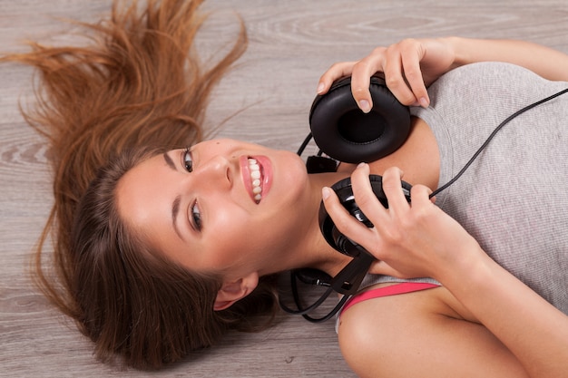 Free photo beautiful woman with headphones lying on the floor