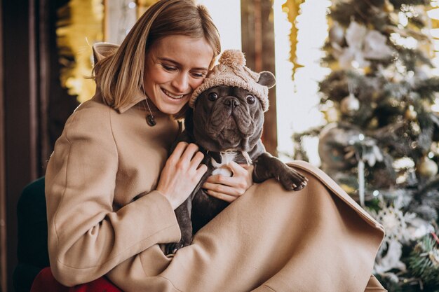 Beautiful woman with her cute french bulldog in warm outfit