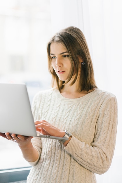 Free Photo beautiful woman with laptop near window