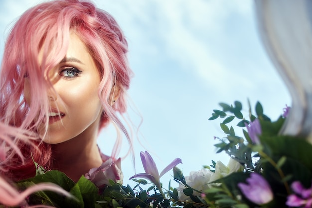 Free photo beautiful woman with pink hair holds large bouquet with greenery and violet flowers