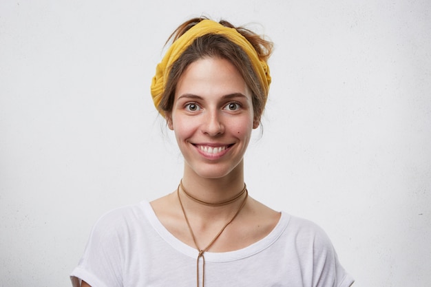 Free photo beautiful woman with pure skin, dark eyes and pleasant smile having yellow headband on head, wearing pendant on her neck