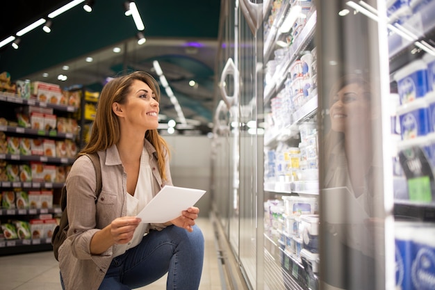 Free photo beautiful woman with shopping list buying food in supermarket