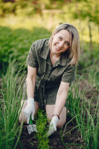 Beautiful woman works in a garden near the house