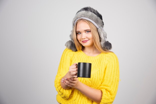 Beautiful woman in yellow sweater holding cup of tea.