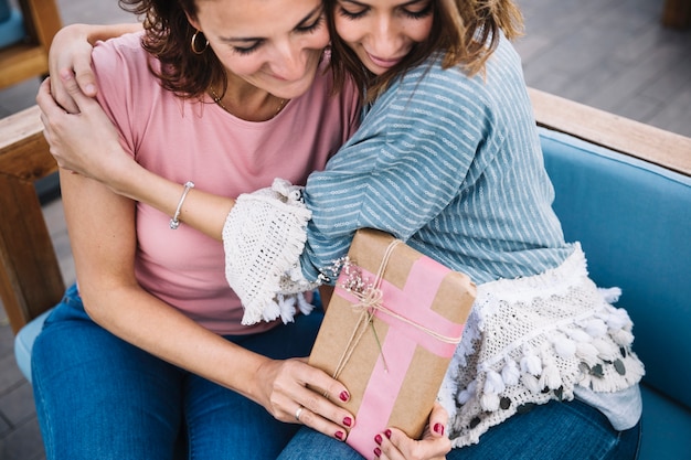 Free photo beautiful women with present hugging on sofa