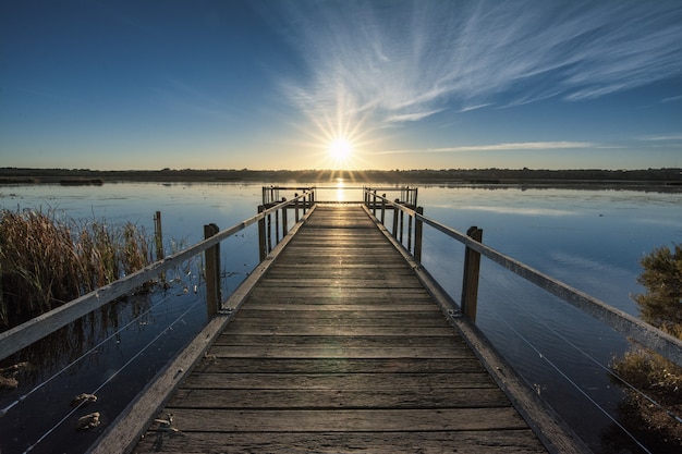 Free Photo beautiful wooden pier by the calm ocean with the beautiful sunset over the horizon