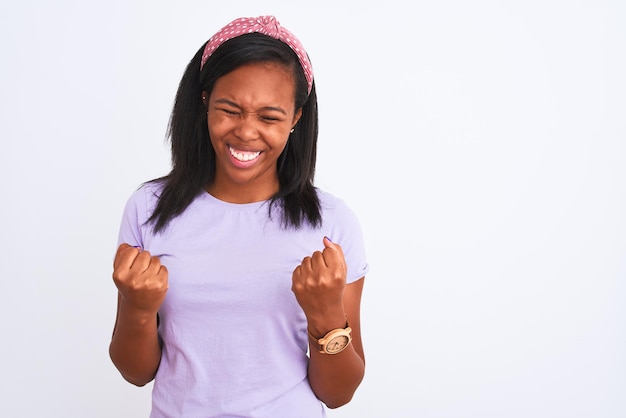 Beautiful young african american woman wearing a diadem over isolated background very happy and excited doing winner gesture with arms raised smiling and screaming for success Celebration concept