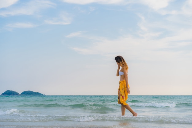 Beautiful young Asian woman happy relax walking on beach near sea. 