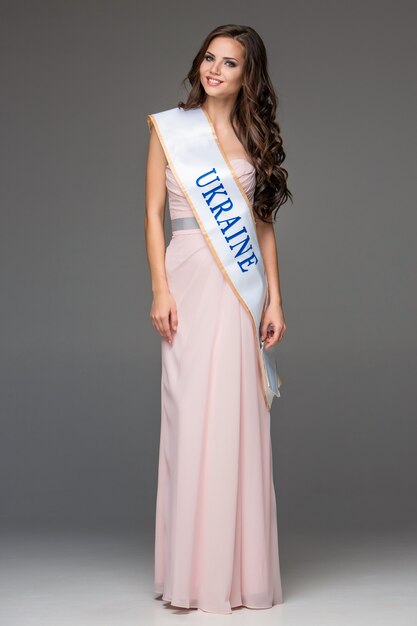 Beautiful young brunette woman with her hair posing in a i long dress.  