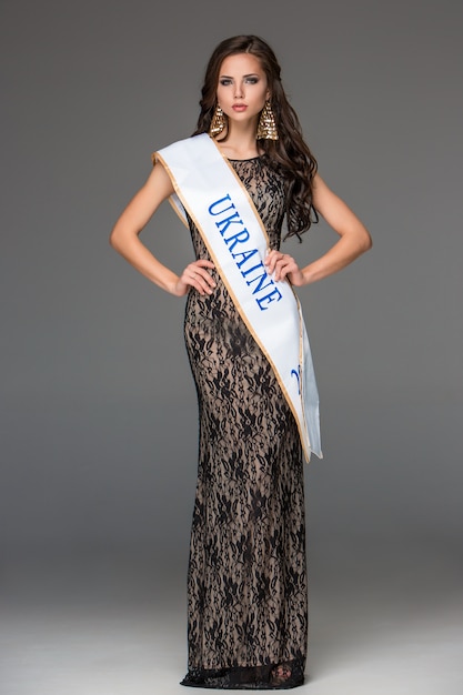 Beautiful young brunette woman with her hair posing in a i long dress.  