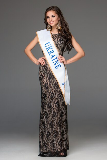 Beautiful young brunette woman with her hair posing in a i long dress.  