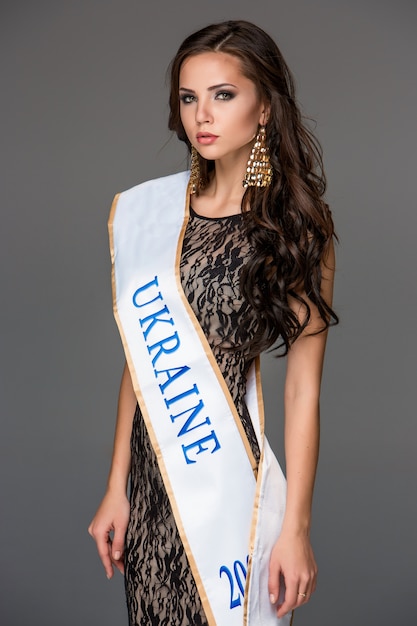 Beautiful young brunette woman with her hair posing in a tracery dress.  