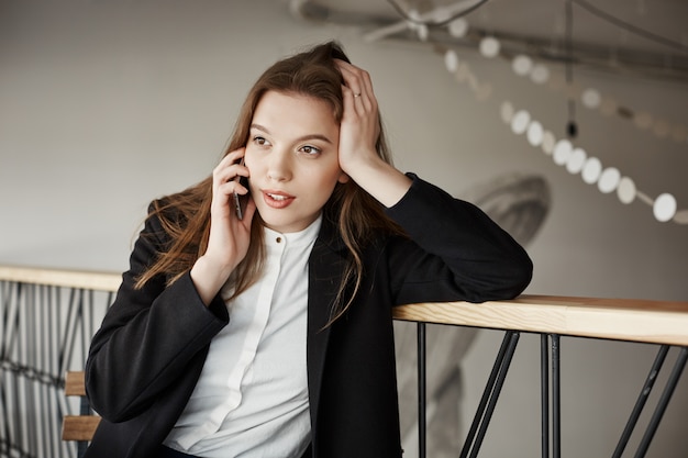 Beautiful young businesswoman at cafe talking by phone