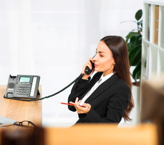 Free photo beautiful young businesswoman shrugging while talking on telephone