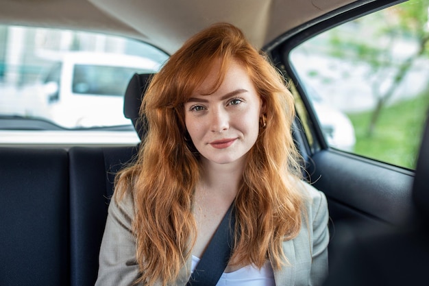 Free photo beautiful young businesswoman sitting on back seat of a car