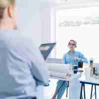 Free photo beautiful young businesswoman sitting on chair listening to her colleague in meeting