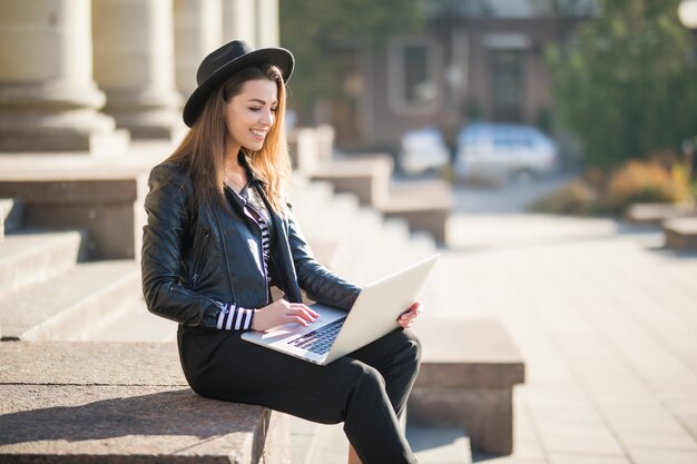 Beautiful young businesswoman student girl works with her brand laptop computer