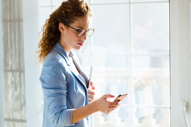 Beautiful young businesswoman using her mobile phone in the office.