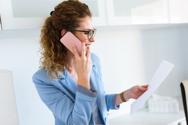 Beautiful young businesswoman using her mobile phone in the office.