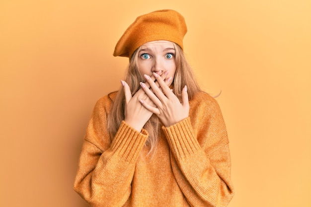 Free photo beautiful young caucasian girl wearing french look with beret shocked covering mouth with hands for mistake. secret concept.