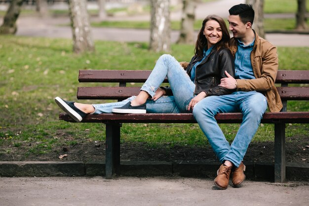 Beautiful young couple relaxing on a bench in the park