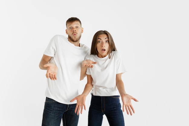 Beautiful young couple's portrait isolated on white studio background. Facial expression, human emotions, advertising concept. Copyspace. Woman and man look shocked, astonished and wondered.