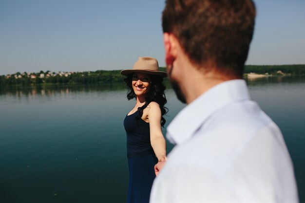 Beautiful young couple spends time on the wooden pier on the lake