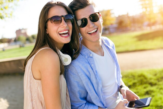 Beautiful young couple using they mobile phone in the park.