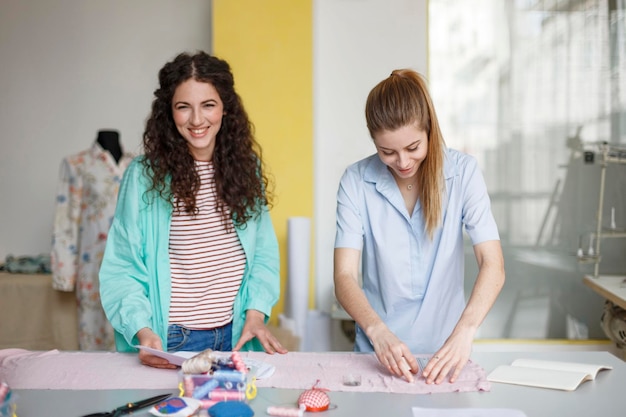 Free photo beautiful young designers happily working together with new textile in modern sewing workshop