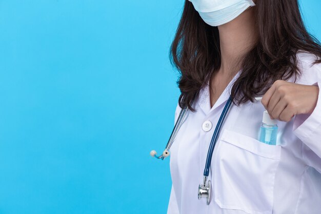 Beautiful young doctor is wearing mask while holding hands gel with rubber