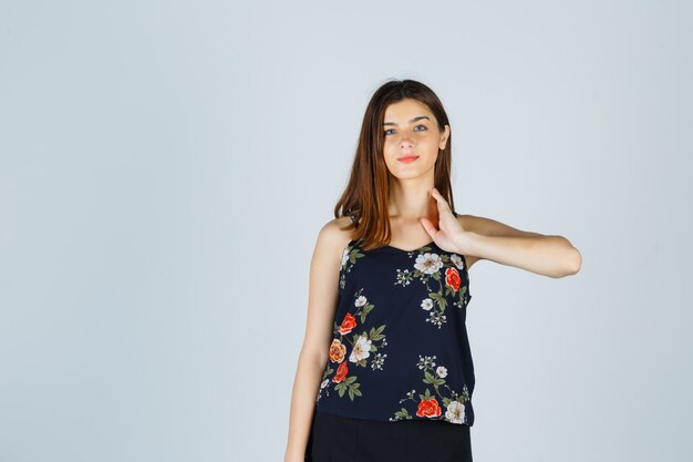 Beautiful young female in blouse, skirt posing while touching her neck