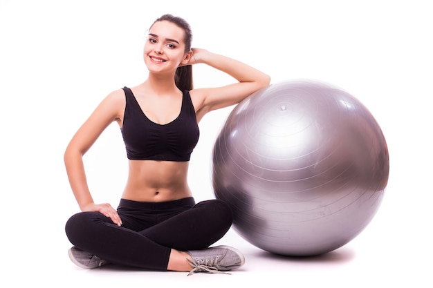 Beautiful young fitness woman with gym ball exercising, isolated on white background