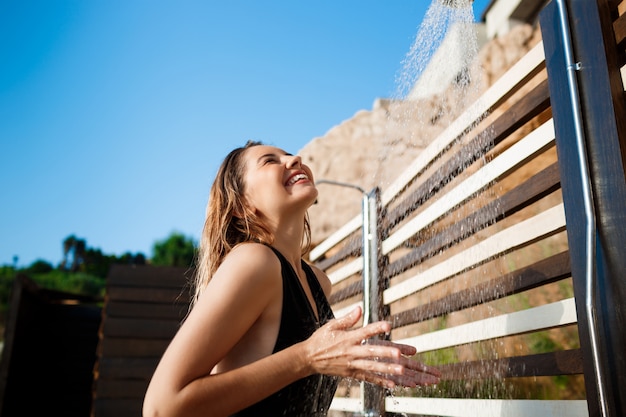 Beautiful young  girl dressed in swimwear taking a shower on beach