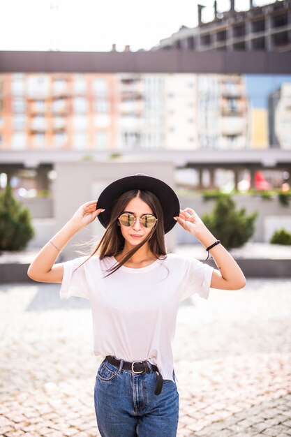 Beautiful young girl posing in hat on the street