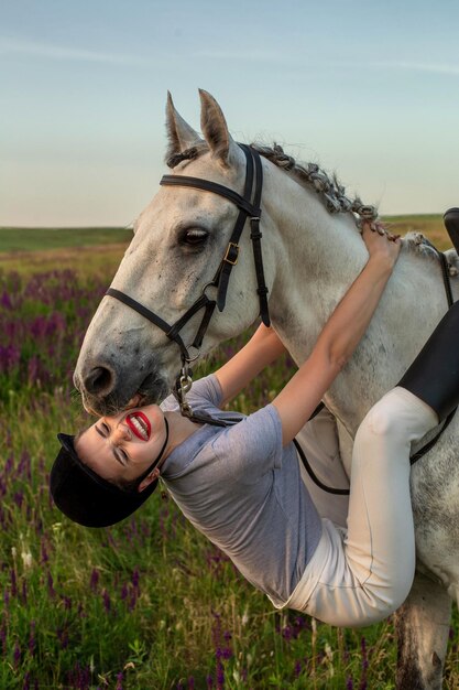 Beautiful young girl smile at her horse dressing uniform competition: outdoors portrait on sunset. Taking care of animals, love and friendship concept.