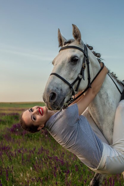 Beautiful young girl smile at her horse dressing uniform competition: outdoors portrait on sunset. Taking care of animals, love and friendship concept.