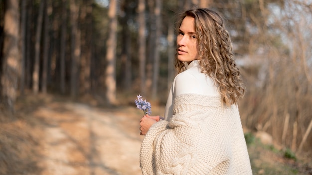 Free photo beautiful young girl with curly hair holding a flower