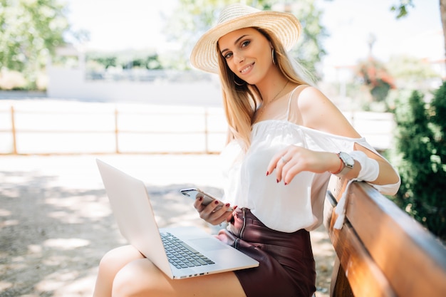 Beautiful young girl with laptop in summer park