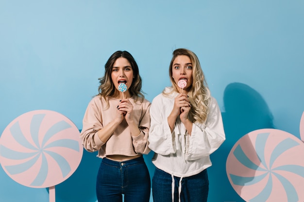 Beautiful young ladies licking lollipops