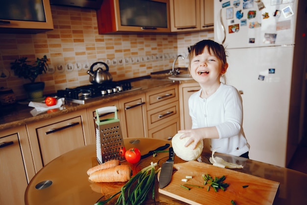 Free photo a beautiful young little daughter is cooking in the kitchen at home