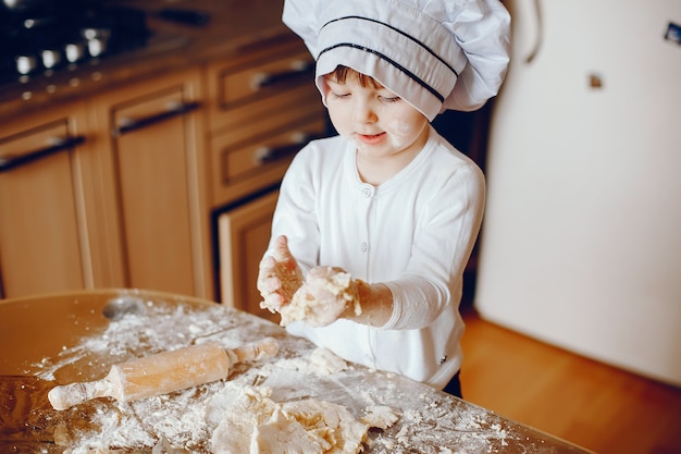 A beautiful young little daughter is cooking in the kitchen at home