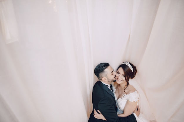 A beautiful young man wearing a black suit standing along with his bride