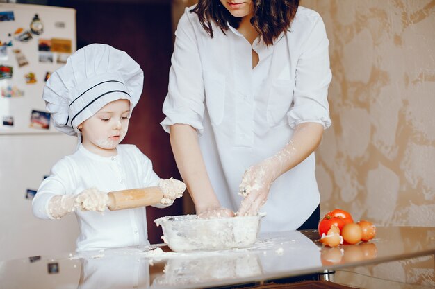 A beautiful young mother with her little daughter is cooking in the kitchen at home