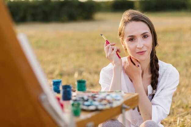 Beautiful young painter looking at camera