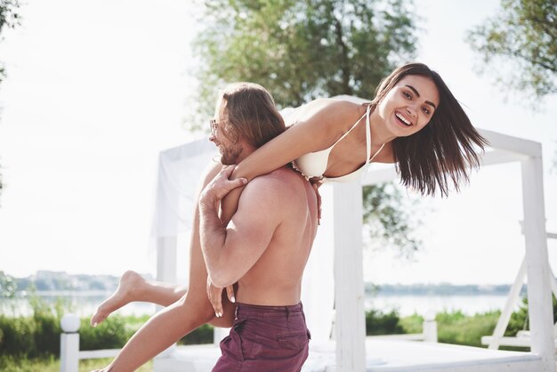 Beautiful young people are fond of it. A man holds a woman on his shoulders, they are playful and romantic.