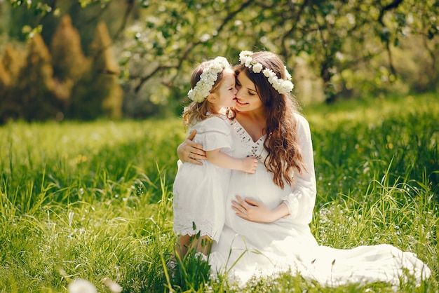 beautiful young pregnant girl in a long white dress playing with little girl